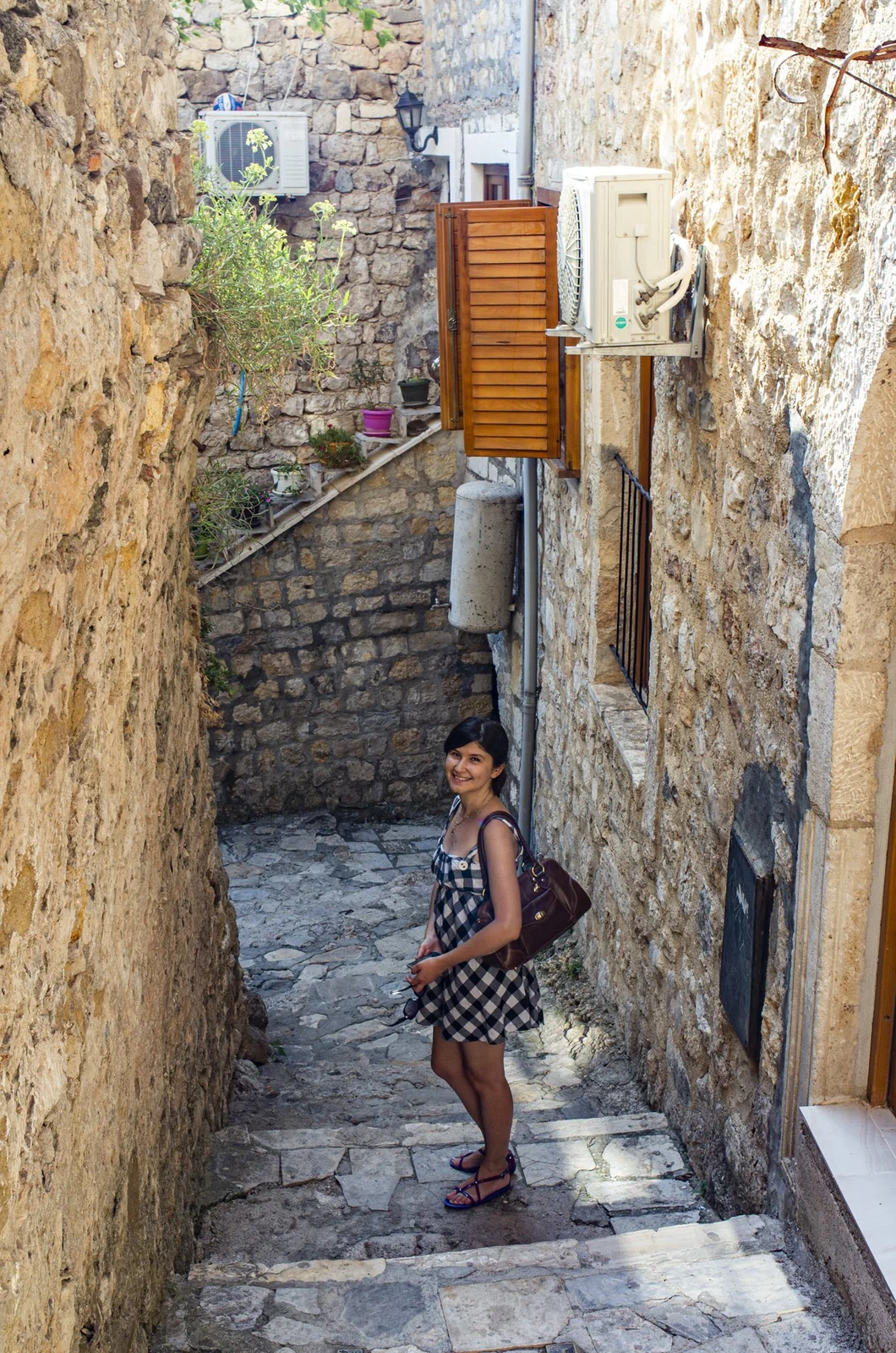 Travel blogger Ket standing in a narrow cobblestone alley in Ulcinj old town, surrounded by ancient stone walls, Montenegro