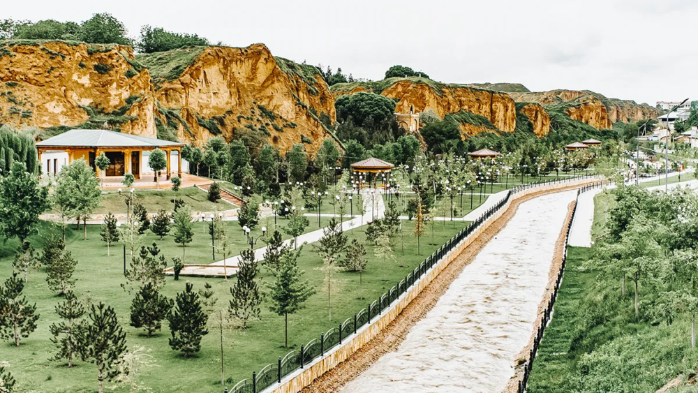Riverside park in Samarkand with landscaped gardens and cliffs along the canal