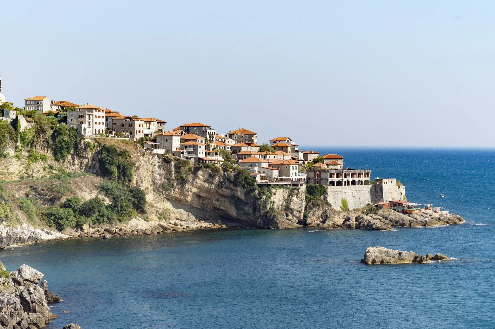 Ulcinj old town perched on a rocky cliff above the Adriatic Sea, Montenegro, with stone buildings and orange-tiled roofs